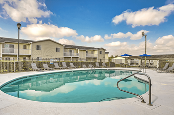 A swimming pool surrounded by chairs and apartment buildings.at Patriot Point Apartment Homes, North Carolina 